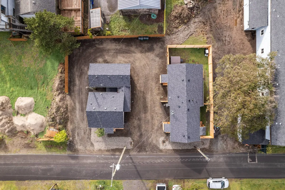 The image shows two charming cottages surrounded by lush greenery and a gravel driveway. The peaceful setting hints at both relaxation after a day of adventure and the community atmosphere where guests can gather outdoors, enjoy morning coffee, or barbecue with neighbors.