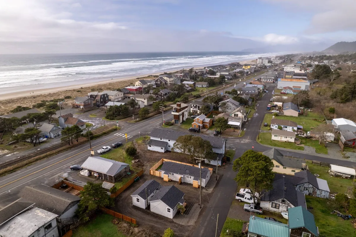 This image captures a broad, inviting view of the ocean with houses in the foreground and a nearby road leading to the beach. The scene suggests easy access to coastal adventures like beach walking, surfing, and exploring local shops. The tranquil ocean backdrop highlights the beauty and vibrancy of the northern Oregon Coast.