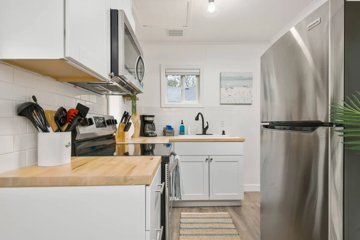 A vibrant kitchen scene with stainless steel appliances, a warm wooden countertop, colorful utensils, and coastal-themed wall art. The space is bright, cheerful, and functional, encouraging socializing and meal prep.
